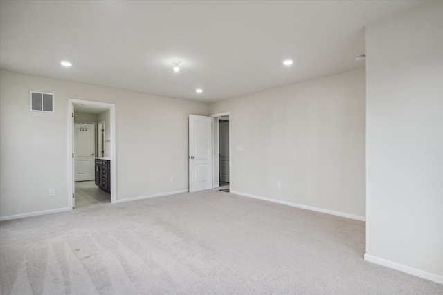 unfurnished bedroom featuring light carpet and ensuite bath