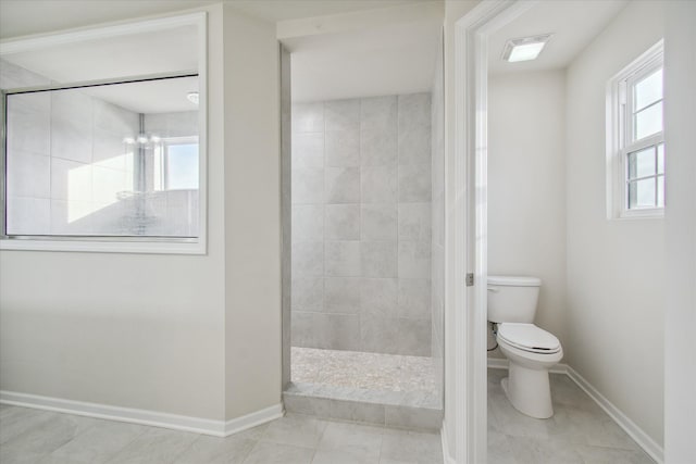 bathroom featuring a tile shower, tile patterned floors, plenty of natural light, and toilet