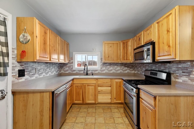 kitchen featuring backsplash, light brown cabinetry, sink, and appliances with stainless steel finishes