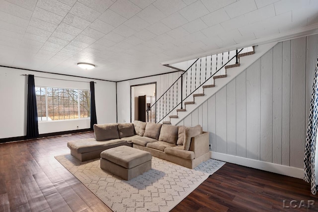 living room with wood walls, wood-type flooring, and ornamental molding