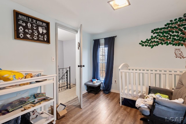 bedroom with hardwood / wood-style floors and a nursery area