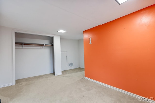 unfurnished bedroom featuring a closet and light colored carpet