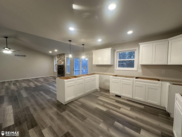 kitchen with lofted ceiling, white cabinetry, hanging light fixtures, dark hardwood / wood-style flooring, and kitchen peninsula