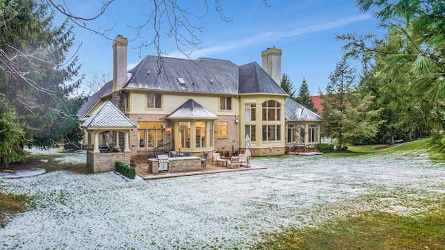 snow covered house featuring area for grilling, a sunroom, and a patio