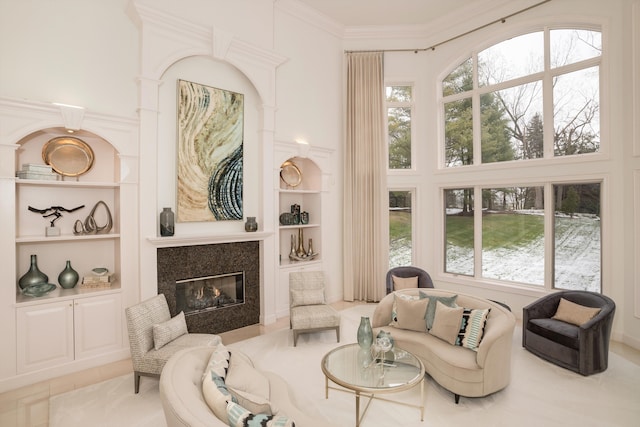 interior space featuring a premium fireplace, crown molding, plenty of natural light, and built in shelves