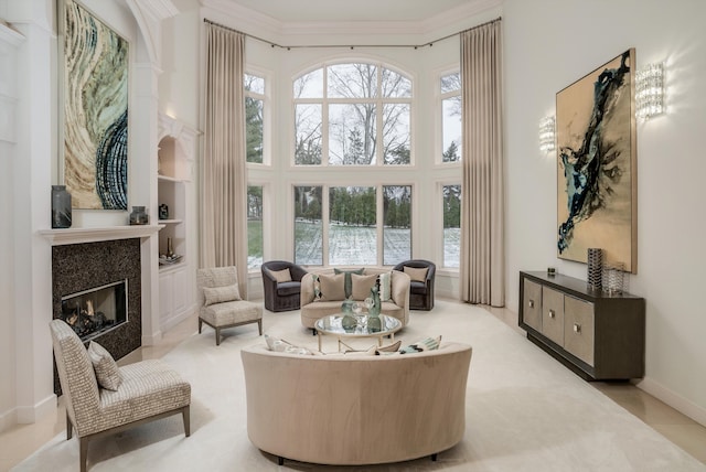 interior space featuring ornamental molding, a high ceiling, a tile fireplace, and built in shelves