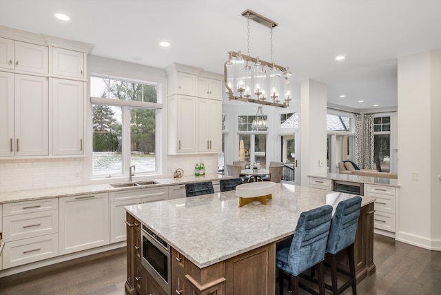 kitchen with dark wood-type flooring, sink, white cabinetry, and stainless steel microwave