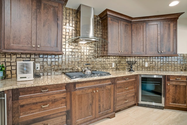 kitchen featuring wine cooler, light stone countertops, stainless steel gas stovetop, and wall chimney range hood