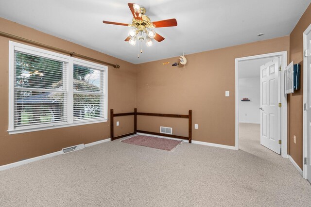 empty room featuring ceiling fan and light colored carpet