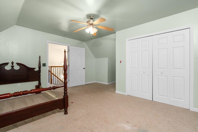 bedroom featuring ceiling fan, a closet, light colored carpet, and vaulted ceiling