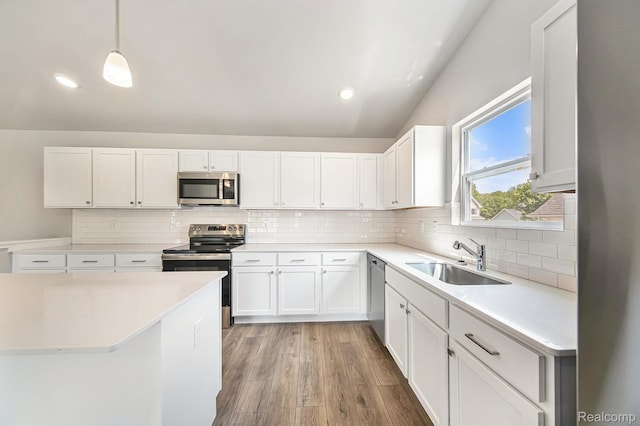 172 Woodland Way, Manchester, MI 48158 - kitchen with stainless steel appliances, light countertops, vaulted ceiling, tasteful backsplash, and light wood-type flooring