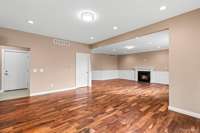 unfurnished living room featuring hardwood / wood-style flooring and crown molding