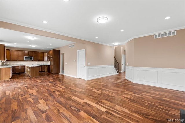 unfurnished living room featuring sink, dark hardwood / wood-style flooring, and ornamental molding