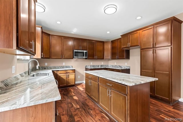 kitchen with light stone counters, sink, a kitchen island, and dark hardwood / wood-style floors