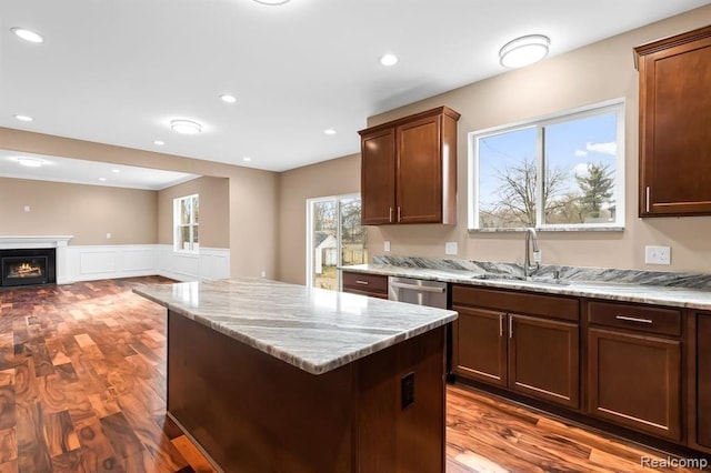 kitchen featuring hardwood / wood-style flooring, dishwasher, light stone counters, and sink