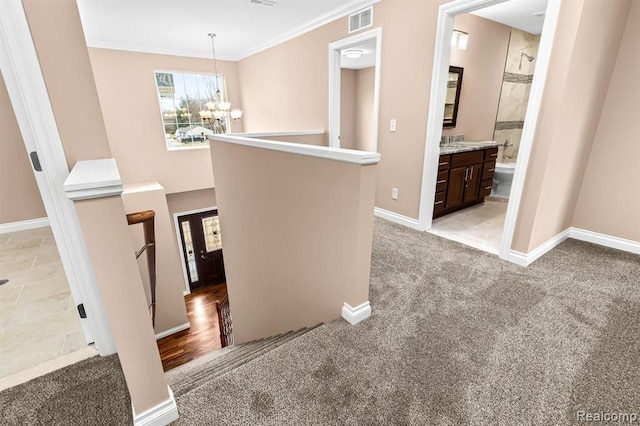 hall featuring light carpet, ornamental molding, and a notable chandelier