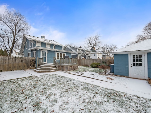 snow covered rear of property with a deck