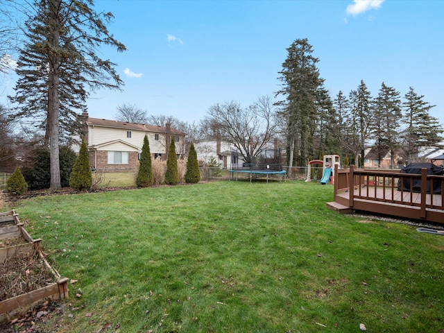 view of yard with a playground, a trampoline, and a deck