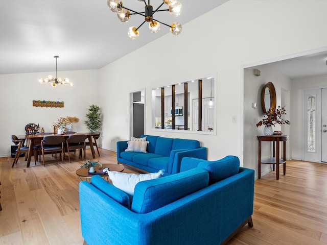 living room featuring vaulted ceiling, light wood-type flooring, and a chandelier