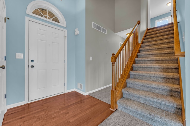 foyer featuring wood-type flooring and a high ceiling