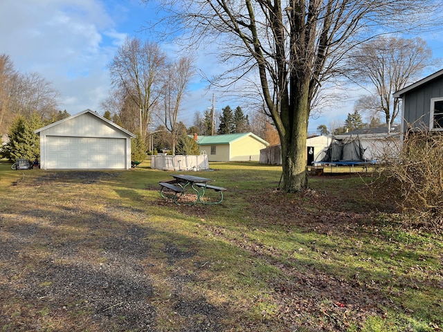 view of yard featuring a garage, an outdoor structure, and a trampoline