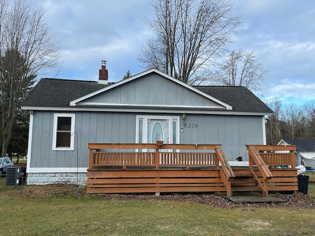 back of property with a deck and a yard