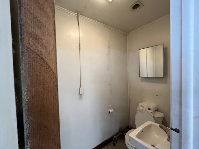 bathroom with toilet, crown molding, and sink