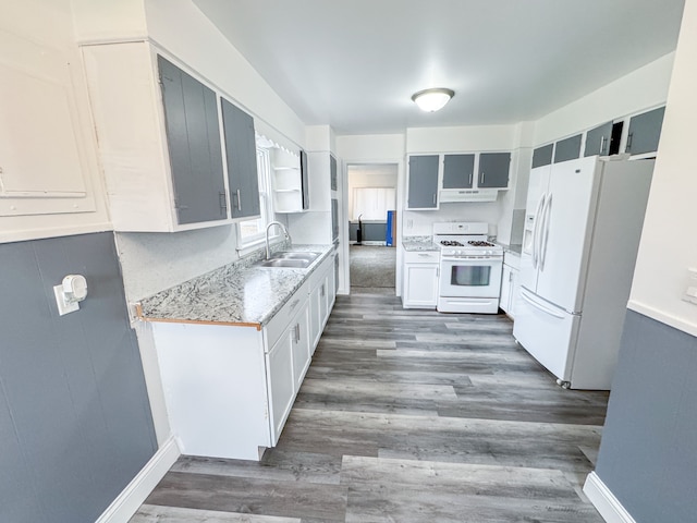 kitchen featuring white appliances, white cabinets, sink, dark hardwood / wood-style floors, and light stone counters