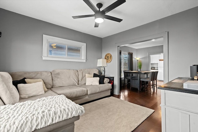 living room featuring ceiling fan and dark hardwood / wood-style floors