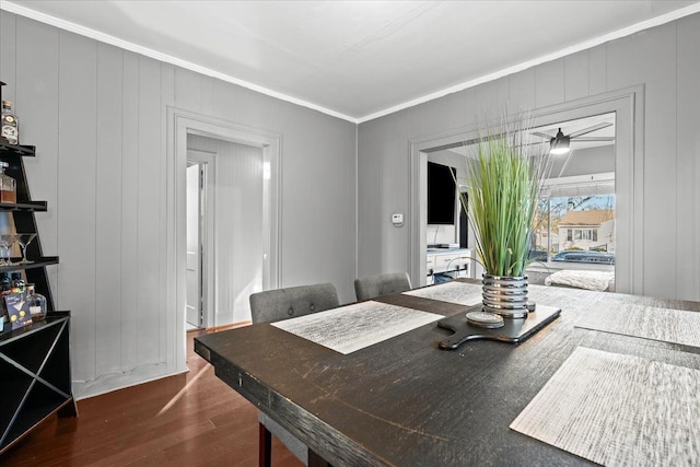 dining space featuring crown molding, wood walls, and dark hardwood / wood-style floors