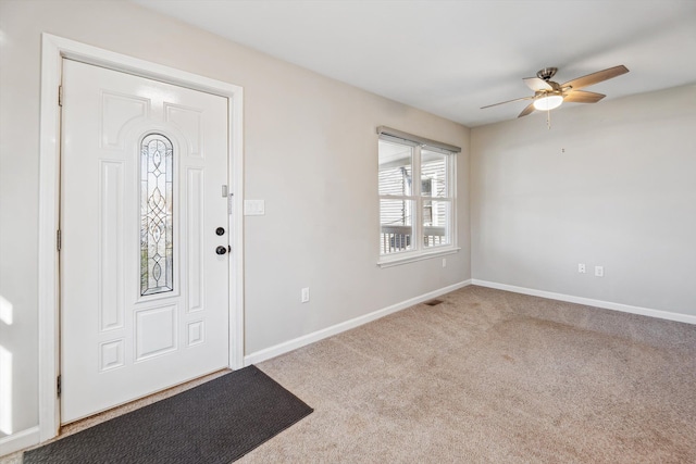 foyer entrance with ceiling fan and light colored carpet