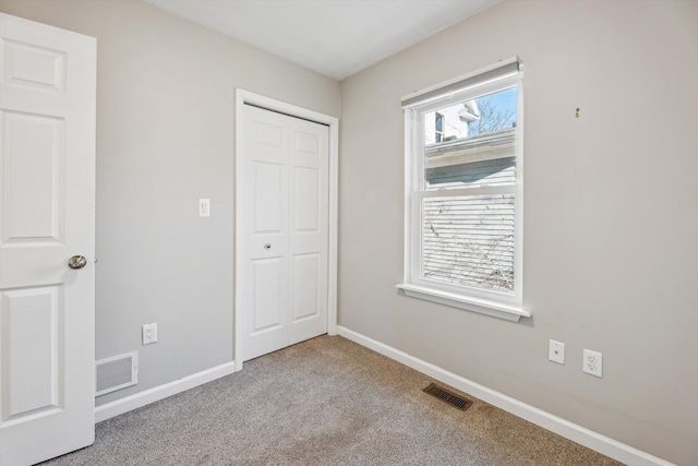 unfurnished bedroom with light colored carpet and a closet