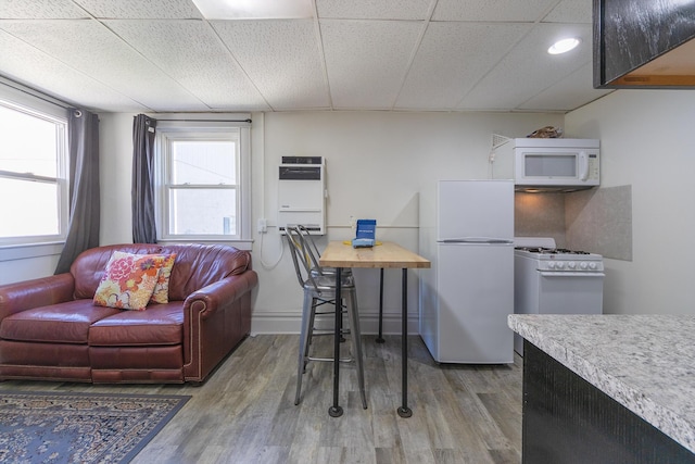 kitchen featuring a paneled ceiling, hardwood / wood-style floors, heating unit, and white appliances