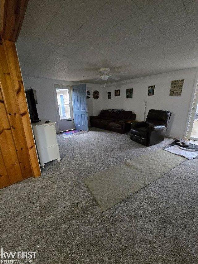 carpeted living room with ceiling fan