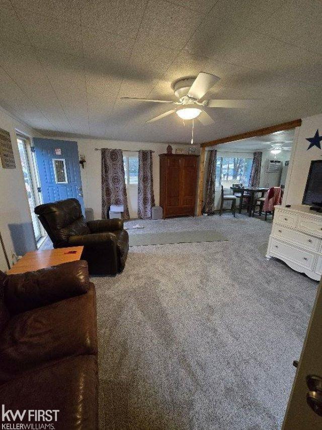 carpeted living room with ceiling fan