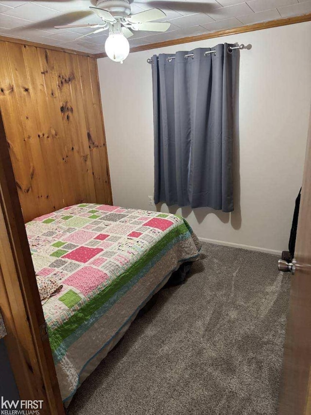 bedroom featuring carpet flooring, ceiling fan, crown molding, and wood walls