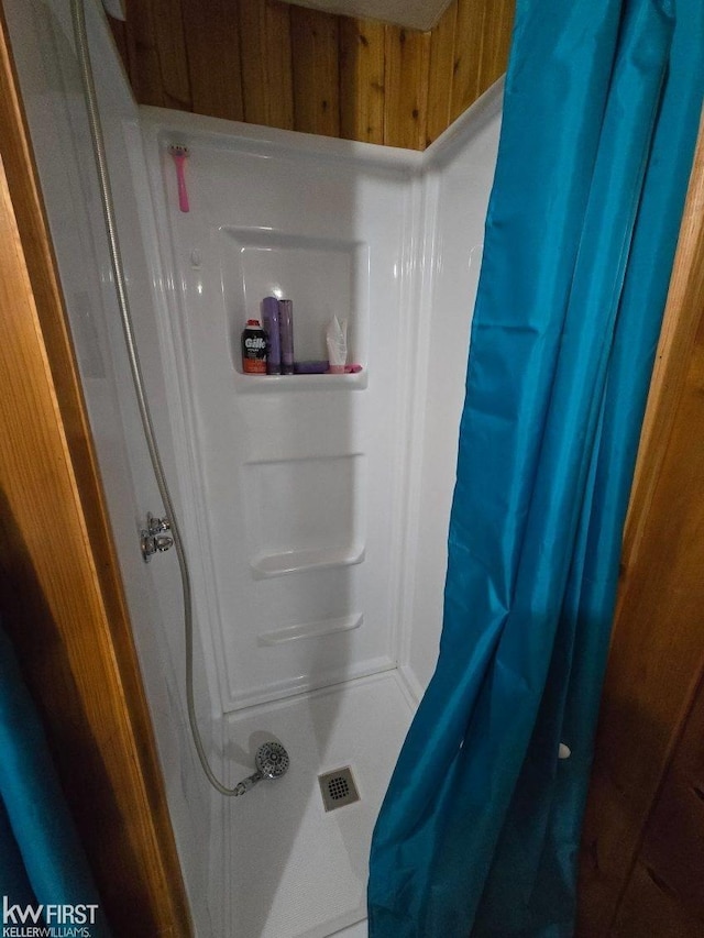 bathroom with a shower with shower curtain and wood walls