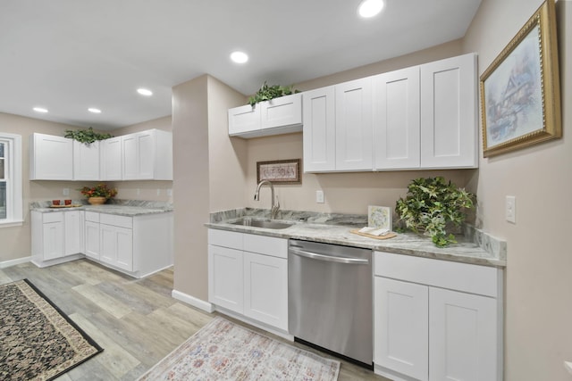 kitchen featuring light stone countertops, light wood-type flooring, stainless steel dishwasher, sink, and white cabinets