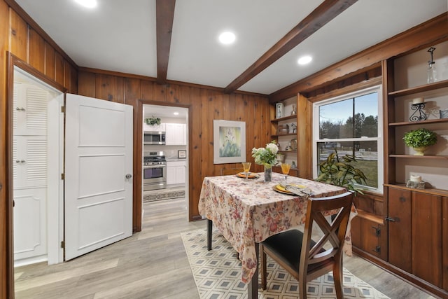 dining area featuring beamed ceiling, light hardwood / wood-style floors, and wood walls