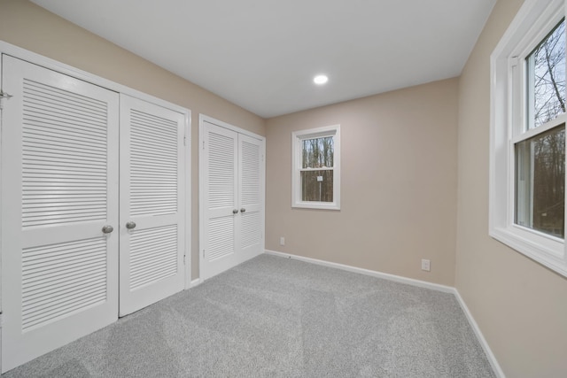 unfurnished bedroom with light colored carpet and two closets