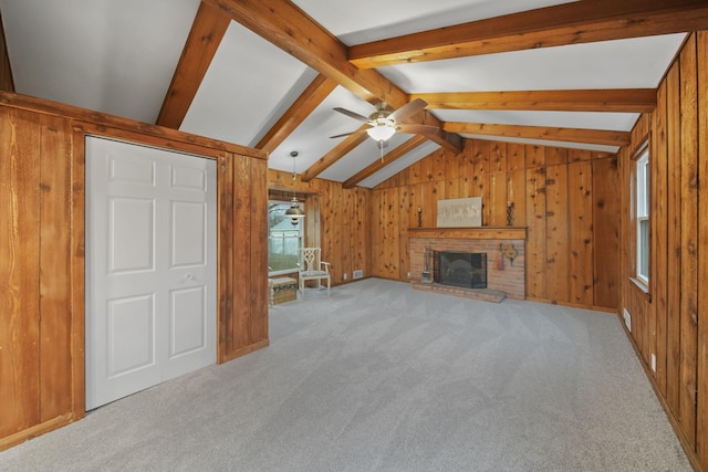 unfurnished living room with vaulted ceiling with beams, ceiling fan, light colored carpet, and a brick fireplace