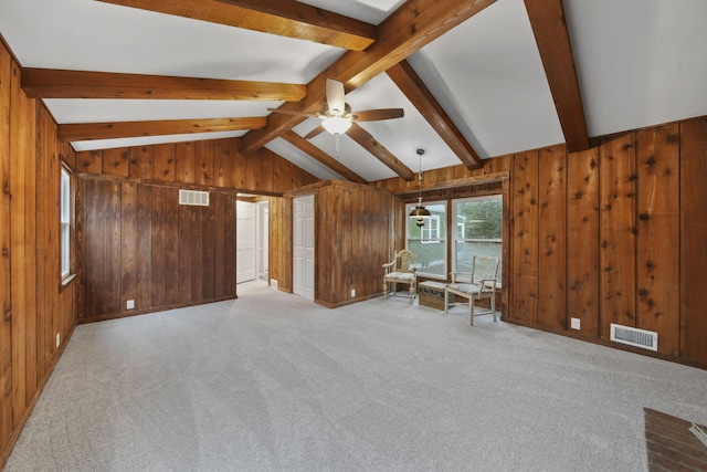 interior space with wood walls, vaulted ceiling with beams, ceiling fan, and light carpet