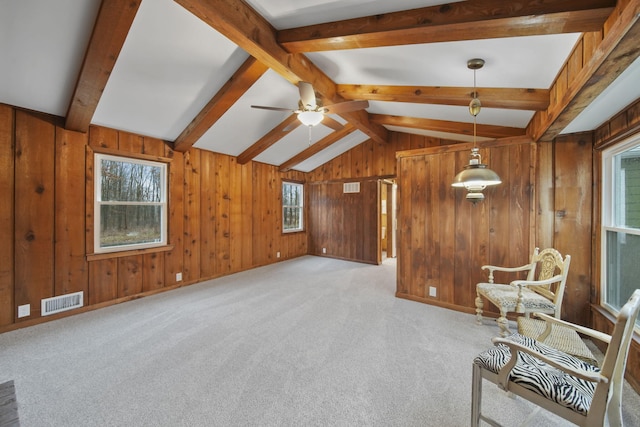 unfurnished room with wood walls, lofted ceiling with beams, ceiling fan, and light colored carpet