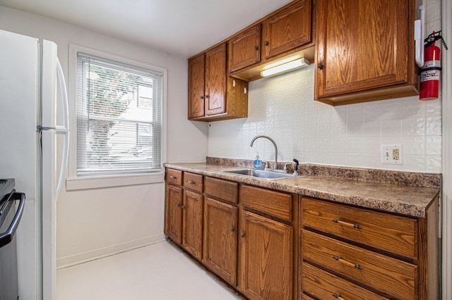 kitchen with decorative backsplash, white refrigerator, stainless steel stove, and sink