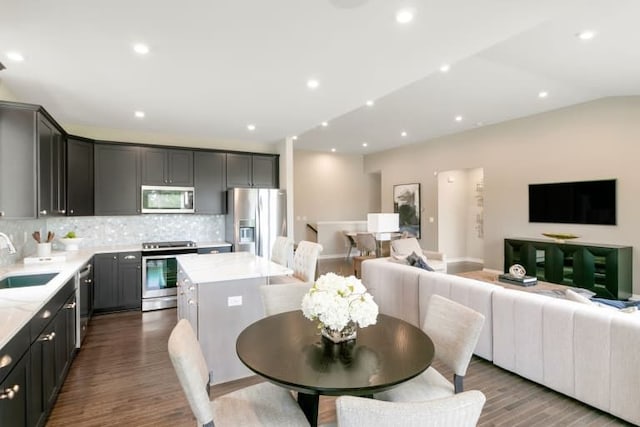 dining area featuring vaulted ceiling, sink, and hardwood / wood-style floors