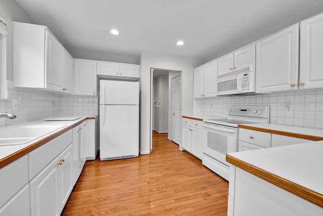 kitchen featuring white cabinetry, sink, decorative backsplash, white appliances, and light hardwood / wood-style flooring