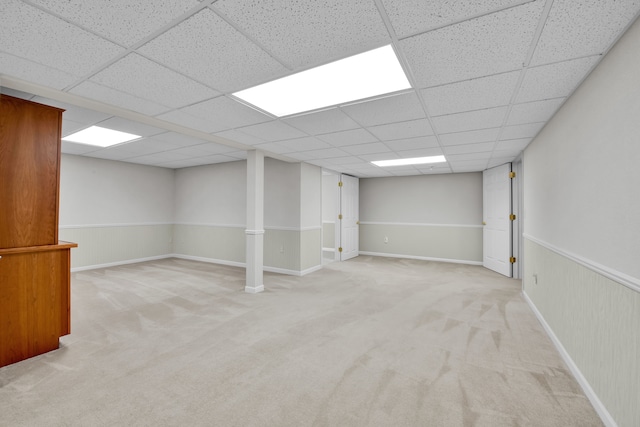 basement featuring a drop ceiling and light colored carpet