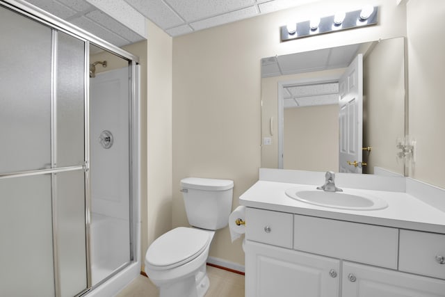 bathroom featuring a paneled ceiling, vanity, toilet, and a shower with shower door