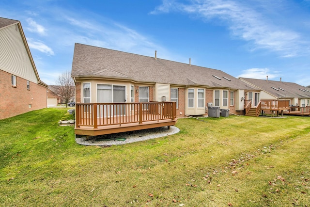 rear view of house with cooling unit, a deck, and a lawn