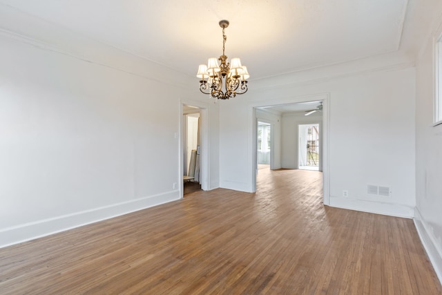 spare room with wood-type flooring, an inviting chandelier, and ornamental molding